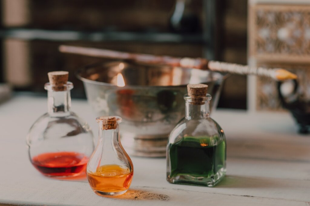 Sur une table des fioles sont disposées et on voit à l’intérieur des huiles de différentes couleurs. / Comment faire ses produits cosmétiques naturels ?